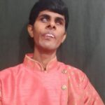 Photo of Artist Mari Muthu wearing a pink shirt on a dark background